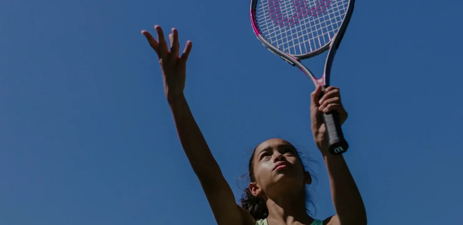 Girl serving a tennis ball